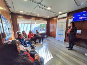 Directora Regional de Migraciones de los Ríos presentando en una sala el programa "Apoya Mujer Migrante" a grupo de mujeres extranjeras